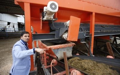 Palestinian engineer Maher Magalsay, who specializes in renewable energy at the Polytechnic University of Hebron, stands by a machine sorting cow dung at the Jebrini dairy farm in the West Bank town of Hebron, where manure is used to produce electricity as an alternative power source, April 10, 2017. (AFP Photo/Hazem Bader)