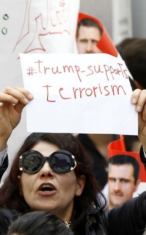 A Syrian protester holds a placard during a demonstration outside the United Nation's office in the capital Damascus, on April 11, 2017, in support of their country's President Bashar Assad. (AFP PHOTO / Louai Beshara)