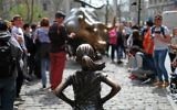 The "Fearless Girl" (front) statue stands facing the "Charging Bull" as tourists take pictures in New York on April 12, 2017. (AFP/ Jewel SAMAD)