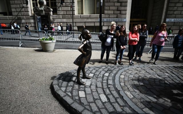 The "Fearless Girl" statue stands facing the "Charging Bull" as people take pictures in New York on April 12, 2017. (AFP/ Jewel SAMAD)