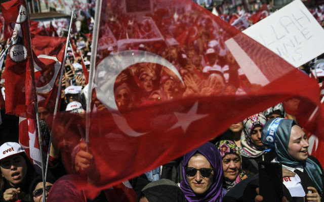 People cheer and wave the national flag as Turkey's president delivers a speech during a rally on the eve of the constitutional referendum, on April 15, 2017 in Istanbul. (Bulent Kilic/AFP)
