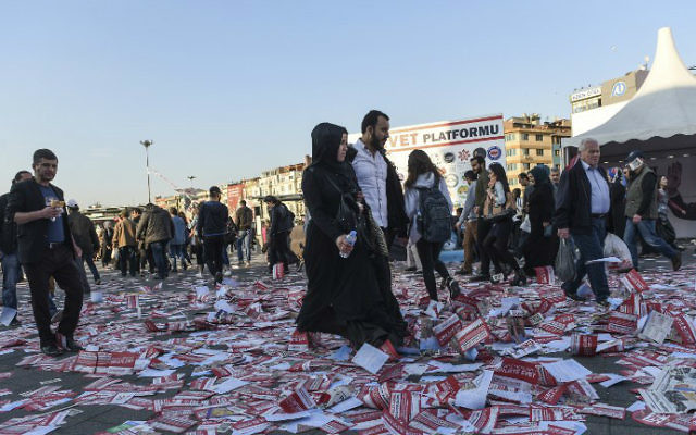 A couple walk on leaflets reading "yes" thrown on the ground at the Kadikoy district, in Istanbul, on the eve of the constitutional referendum, on April 15, 2017. (Bulent Kilic/AFP)