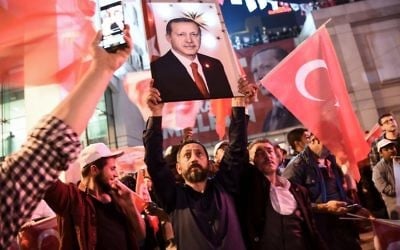 A supporter of the 'Yes' campaign brandishes a picture of Turkish president Recep Tayyip Erdogan among other supporters waving Turkish national flags at a rally near the headquarters of the conservative Justice and Development Party (AKP) on April 16, 2017 in Istanbul after the initial results of a nationwide referendum that will determine Turkey's future destiny. (AFP/Ozan Kose)