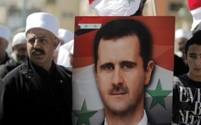 Druze residents of the Masada village in the Golan Heights hold a portrait of Syrian President Bashar Assad during a rally marking Syria's Independence Day on April 17, 2017. (AFP Photo/Jalaa Marey)