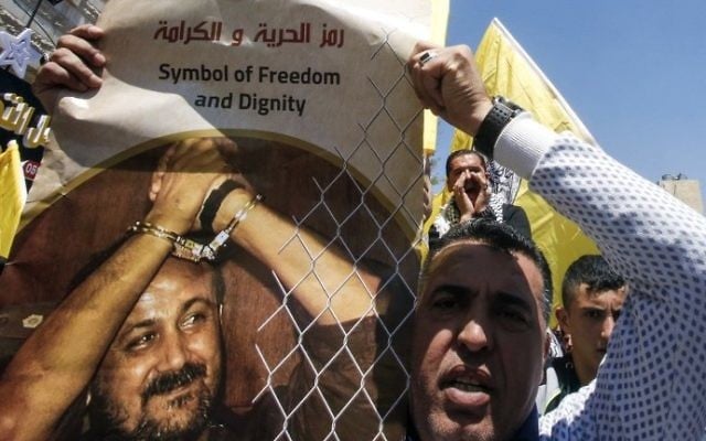 A man holds a photo of Marwan Barghouti calling for his release during a rally supporting Palestinian prisoners detained in Israeli jails in the West Bank city of Hebron on April 17, 2017. (AFP/Hazem Bader) A man holds a photo of Marwan Barghouti calling for his release during a rally supporting Palestinian prisoners detained in Israeli jails in the West Bank city of Hebron on April 17, 2017. (AFP/Hazem Bader)