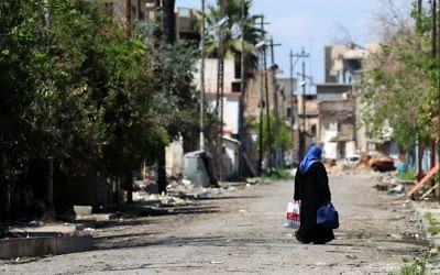 A displaced Iraqi woman from the old city of Mosul walks down a street on April 17, 2017, during an offensive by Iraqi security forces to recapture the city from Islamic State group fighters. (AFP/Ahmad Al-Rubaye)