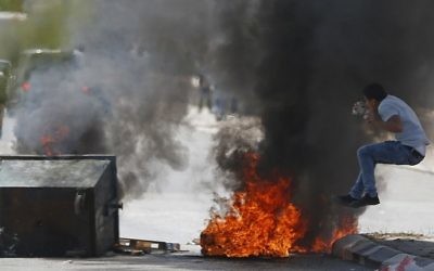 Following a demonstration to show support for Palestinian prisoners on hunger strike in Israeli prisons, a Palestinian protester jumps near a burning tire during clashes with Israeli security forces in the West Bank town of Bethlehem, April 17, 2017. (AFP/Ahmad Gharabli)