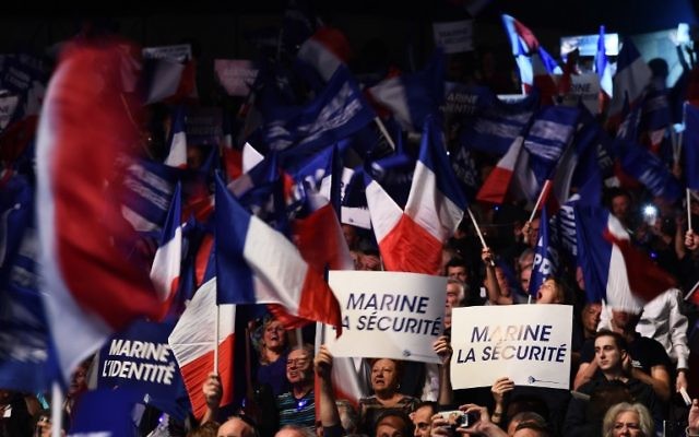 Supporters of French presidential election candidate for the far-right Front National (FN) party Marine Le Pen hold banners and wave French flags during a campaign meeting on April 19, 2017, in Marseille, southern France. (AFP PHOTO / ANNE-CHRISTINE POUJOULAT)