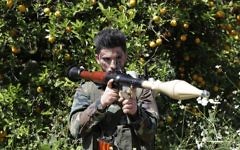 A Hezbollah fighter is seen standing at attention in an orange field near the town of Naqura on the Lebanese-Israeli border on April 20, 2017. (AFP PHOTO / JOSEPH EID)