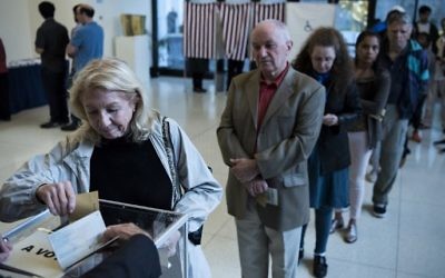 A French citizen casts her ballot while others wait in line while voting in the country's presidential election at the Embassy of France on April 22, 2017 in Washington, DC. (AFP PHOTO / Brendan Smialowski)
