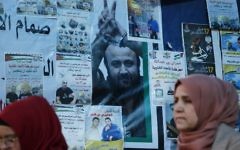 Palestinian women walk past a wall bearing posters, including a portrait of prominent prisoner Marwan Barghouti, during a rally in Ramallah, in support of him and other prisoners on hunger strike in Israeli jails on April 24, 2017. (AFP/Abbas Momani)