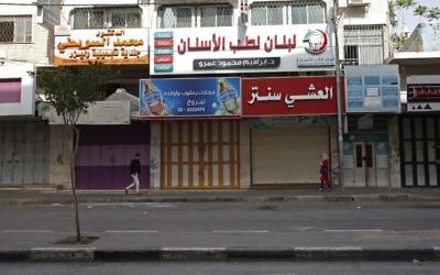 Palestinians walk past closed shops in the West Bank town of Hebron on April 27, 2017, during a trade strike in support of Palestinian prisoners on hunger strike in Israeli jails. (Hazem Bader/AFP)