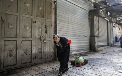 An elderly woman pulls a makeshift cardboard cart past a closed shop in the Old City of Jerusalem on April 27, 2017, during a trade strike in support of Palestinian prisoners on hunger strike in Israeli jails. (Ahmad Gharabli/AFP)