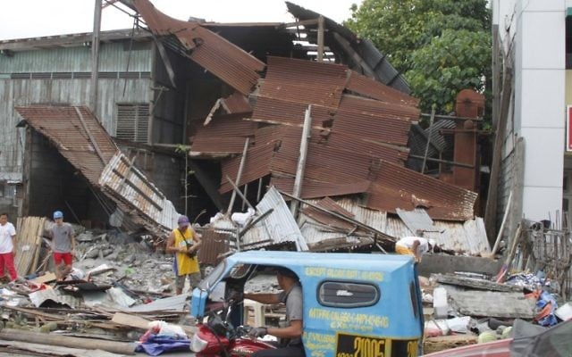 People stand next to debris from a collapsed house after a 6.8-magnitude earthquake hit General Santos City, in southern island of Mindanao on April 29, 2017.( AFP PHOTO / AQUILES ZONIO)