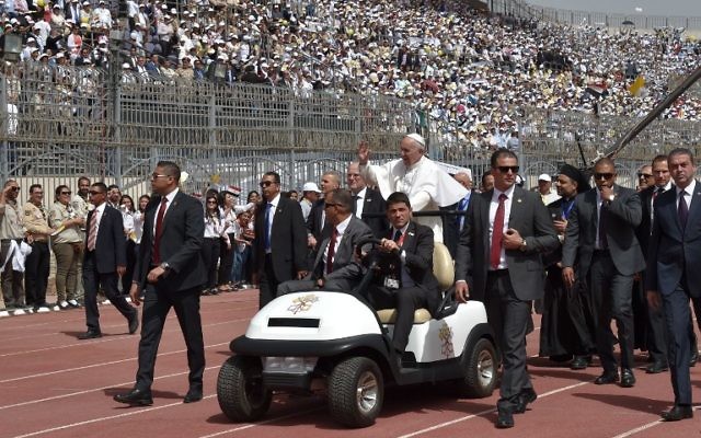 Pope Francis is surrounded by security as he rides an uncovered Popemobile before the start of a mass on April 29, 2017 at a stadium in Cairo. (AFP PHOTO / Andreas SOLARO)