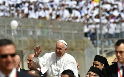 Pope Francis is surrounded by security while waving from above an uncovered Popemobile before the start of a mass on April 29, 2017 at a stadium in Cairo.
( AFP PHOTO / Andreas SOLARO)