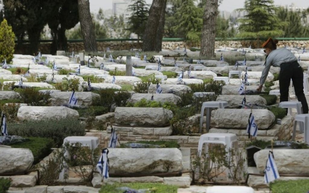 An Israeli soldier lays flowers on the graves of fallen soldiers at the Mount Herzl military cemetery in Jerusalem on April 30, 2017, a few hours ahead of the start of Remembrance Day, commemorating fallen Israeli soldiers. (AFP PHOTO / MENAHEM KAHANA)