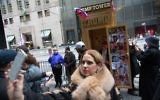 A woman takes a selfie with an outhouse featuring a Trump doll sitting on the toilet in front of Trump Tower in New York during an April Fool's Day event on April 1, 2017 (Kevin Hagen/Getty Images/AFP)