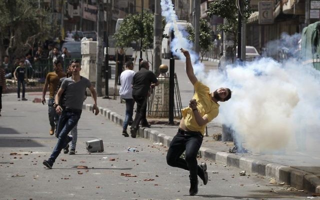 Palestinians throw stones at Israeli troops during clashes in the West Bank city of Hebron, on April 27, 2017. (Wisam Hashlamoun/Flash90)