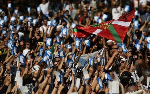 Pro independence Basque followers hold up the symbol of the day called ''Artisans of the Peace'' close to a Basque flag during a meeting after the announcement that ETA handed over its arms in Bayonne, southwestern France, Saturday, April 8, 2017.(AP Photo/Alvaro Barrientos)