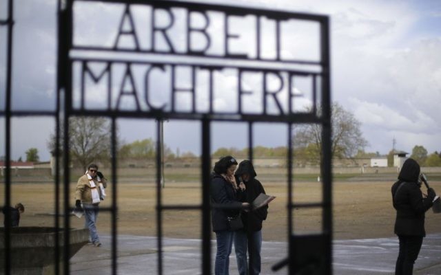 People stand behind the gate with the inscription 'Arbeit macht frei' (work sets you free) at the Sachsenhausen Nazi death camp in Oranienburg, about 35 kilometers north of Berlin, April 23, 2017. Commemorations will be held on Sunday on the occasion of the 72th anniversary of the liberation of the camp. (AP/Markus Schreiber)