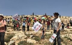 Demonstrators wave Palestinian and Peace Now flags at West Bank protest against settler violence near Michmash Junction, April 28, 2017. (Times of Israel/Jacob Magid)