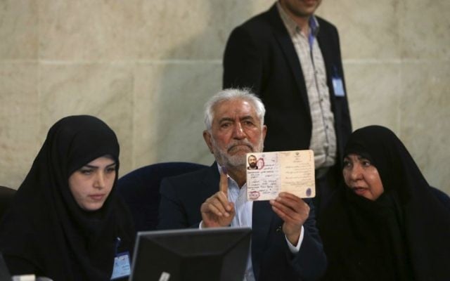 Former Iranian oil minister Mohammad Gharazi (center) shows his inked finger and identification while registering his candidacy for the May 19 presidential elections, accompanied by his wife Zohreh (right), at the Interior Ministry in Tehran, Iran, April 13, 2017. (AP/Vahid Salemi) Former Iranian oil minister Mohammad Gharazi (center) shows his inked finger and identification while registering his candidacy for the May 19 presidential elections, accompanied by his wife Zohreh (right), at the Interior Ministry in Tehran, Iran, April 13, 2017. (AP/Vahid Salemi)