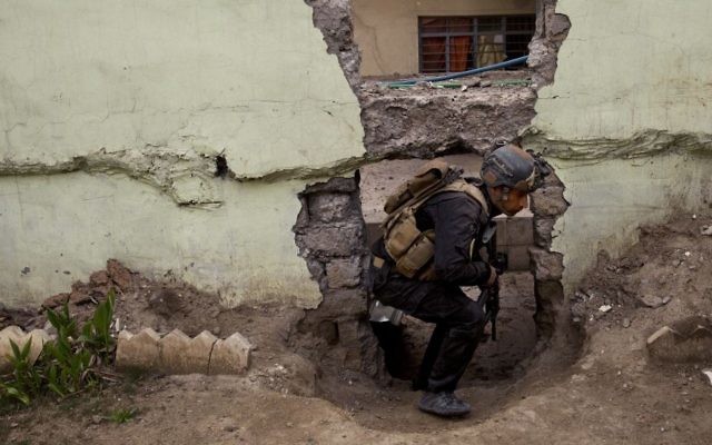 An Iraqi special forces soldier moves through a hole in a wall during heavy fighting in the Yarmouk district of western Mosul, Iraq, Tuesday, April 11, 2017. (AP Photo/Maya Alleruzzo) 