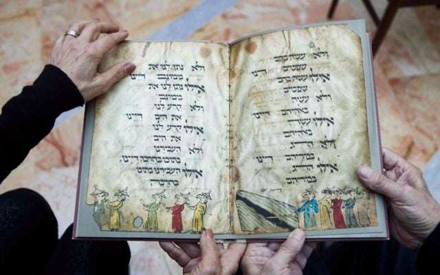In this file photo taken Wednesday, April 13, 2016, Eli and Shuli Barzilai hold a copy of the Birds' Head Haggadah, the text read around Jewish dinner tables on the Passover holiday, in their home in Jerusalem. (AP Photo/Dan Balilty, File)