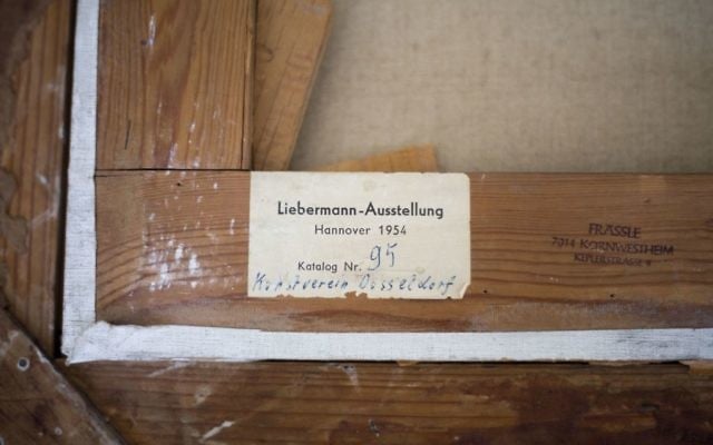 In this photo taken on Wednesday, April 5, 2017, the back side of Max Liebermann's "Basket Weavers" painting hangs in a law office in Jerusalem. Max Liebermann's "Basket Weavers" painting is returning to the American heirs of its original Jewish owner, after it was confiscated by the Nazis, jockeyed by an unscrupulous German art trader and ultimately purchased by an Israeli Holocaust survivor unaware of its murky past. (AP Photo/Ariel Schalit)