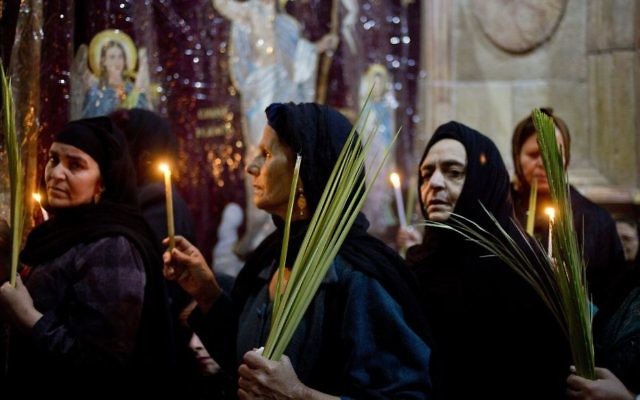 Christians hold candles and palm fonds during the Palm Sunday mass inside the Church of the Holy Sepulchre, traditionally believed by many to be the site of the crucifixion and burial of Jesus, in Jerusalem's Old City, April 9, 2017 during Palm Sunday. (AP Photo/Ariel Schalit)
