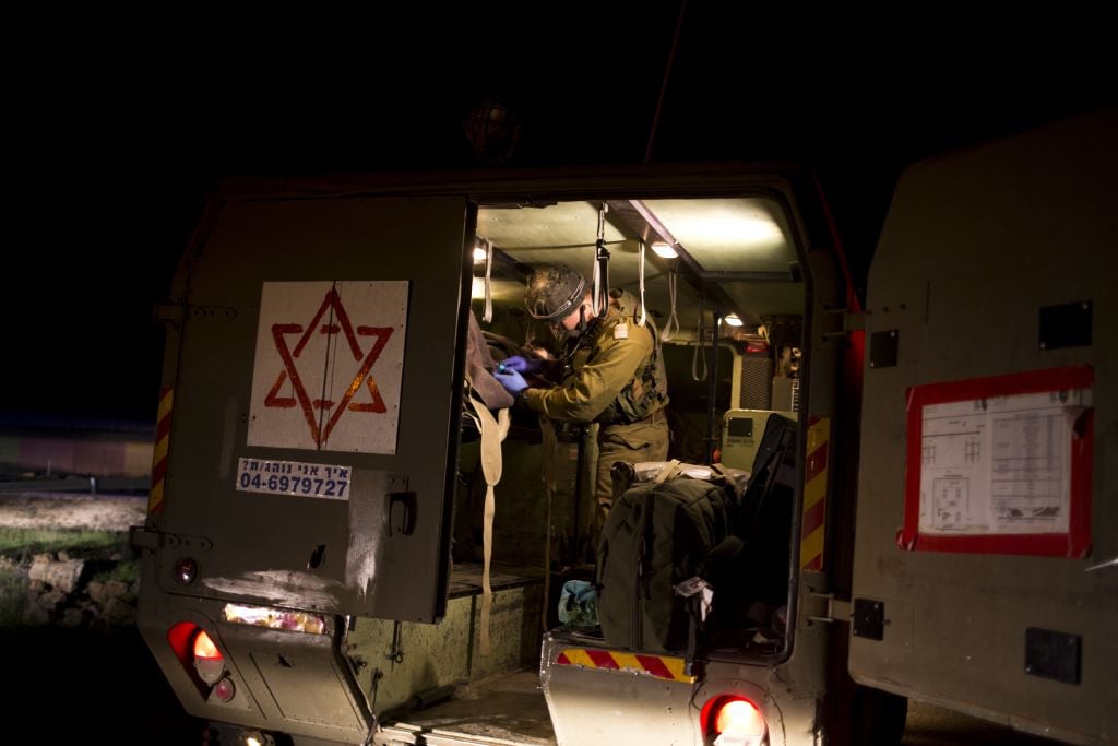 Israeli military medics assist wounded Syrians on April 6, 2017. Seven wounded Syrians who crossed into Israel on Thursday night received immediate treatment and were hospitalized. They are the latest group of Syrians receiving free medical care through an Israeli military program operating since 2013. (AP Photo/Dusan Vranic) Israeli military medics assist wounded Syrians on April 6, 2017. Seven wounded Syrians who crossed into Israel on Thursday night received immediate treatment and were hospitalized. They are the latest group of Syrians receiving free medical care through an Israeli military program operating since 2013. (AP Photo/Dusan Vranic)