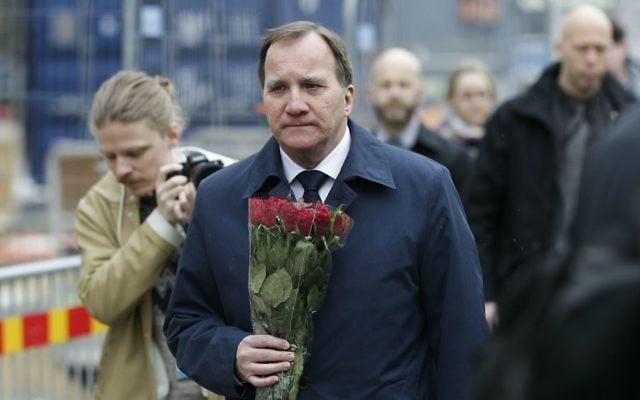 Sweden's Prime Minister Stefan Lofven arrives with flowers at a fence near the department store Ahlens, following a suspected terror attack in central Stockholm, Sweden, Saturday, April 8, 2017. (AP Photo/Markus Schreiber)