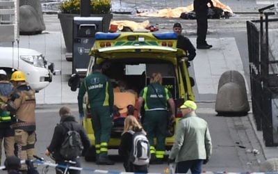 Emergency personnel load a person into an ambulance, center, at the scene after a truck crashed into a department store injuring several people in central Stockholm, Sweden, Friday, April 7, 2017.  ﻿(Fredrik Sandberg/TT News Agency via AP)