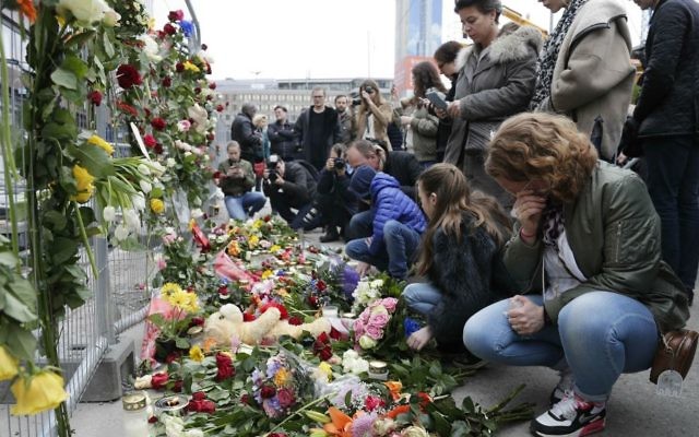 People lay down flowers at a fence near the department store Ahlens following a suspected terror attack in central Stockholm, Sweden, Saturday, April 8, 2017. (AP Photo/Markus Schreiber)