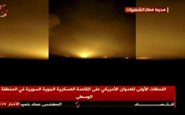 This frame grab from video provided by Ikhbaria TV, a Syrian pro-government TV channel that is consistent with independent AP reporting, shows flames rising from US Tomahawk missiles which hit the Shayrat air base, southeast of Homs, Syria, early Friday April, 7, 2017. The Arabic on the screen reads: 'Around the Shayrat airport, top right, the first moments of the American aggression on the air base in the central region, center bottom.' (Ikhbaria TV, via AP)