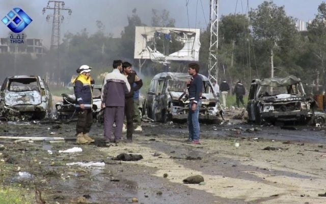 This frame grab from video provided by the Thiqa News Agency, shows rebel gunmen at the site of a blast that damaged several buses and vans at the Rashideen area, a rebel-controlled district outside Aleppo city, Syria, Saturday, April. 15, 2017. (Thiqa News via AP)