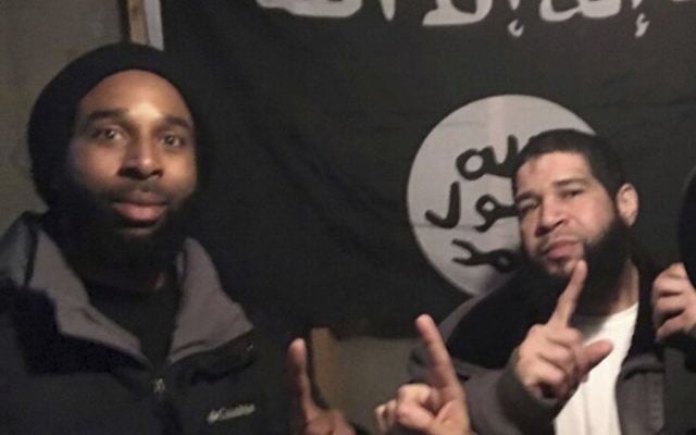 In this undated photo provided by the Federal Bureau of Investigation Joseph D. Jones, left, and Edward Schimenti pose in front of an Islamic State group flag. (FBI via AP) In this undated photo provided by the Federal Bureau of Investigation Joseph D. Jones, left, and Edward Schimenti pose in front of an Islamic State group flag. (FBI via AP)