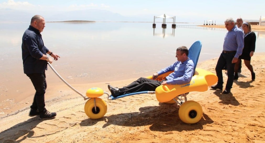 Tamar Regional Council mayor Dov Litvinoff pulls Tourism Minister Yariv Levin in the beach wheelchairs on the new Ein Boqek promenade on April 3, 2017. The promenade has a number of paved paths leading to the water enabling visitors with physical disabilities easier access. (courtesy Mickey Lengental)
