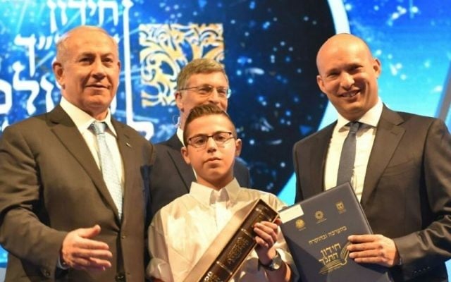 Prime Minister Benjamin Netanyahu, left, and Education Minister Naftali Bennett, right, with Sagiv Lugasi, winner of the annual International Bible Quiz at the Jerusalem Theater, May 2, 2017. (Shlomi Amsalem) Prime Minister Benjamin Netanyahu, left, and Education Minister Naftali Bennett, right, with Sagiv Lugasi, winner of the annual International Bible Quiz at the Jerusalem Theater, May 2, 2017. (Shlomi Amsalem)