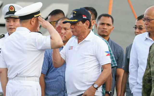 Philippine President Rodrigo Duterte (C) returns a salute from a Chinese naval officer (L) as Philippine Defense Secretary Delfin Lorenzana (R) looks on during Duterte's arrival to visit the guided missile frigate Changchun berthed at the Davao international port on May 1, 2017. (MANMAN DEJETO / AFP) Philippine President Rodrigo Duterte (C) returns a salute from a Chinese naval officer (L) as Philippine Defense Secretary Delfin Lorenzana (R) looks on during Duterte's arrival to visit the guided missile frigate Changchun berthed at the Davao international port on May 1, 2017. (MANMAN DEJETO / AFP)