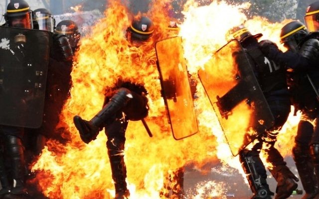 French CRS anti-riot police officers are engulfed in flames as they face protesters during a march for the annual May Day workers' rally in Paris on May 1, 2017. (AFP PHOTO / Zakaria ABDELKAFI)