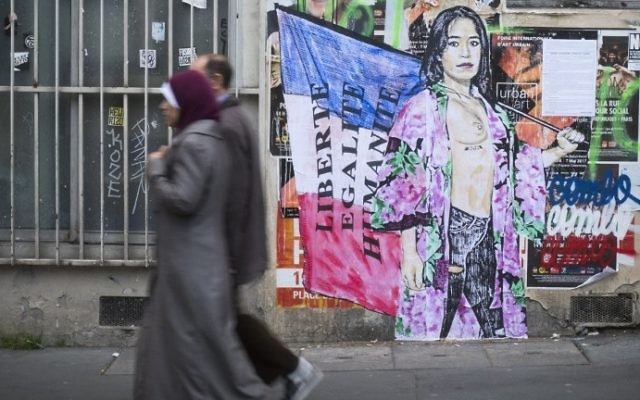 A picture taken in Paris on May 2, 2017 shows a couple walk past a graffiti reading "freedom, equality and brotherhood"  ahead of the second and final round of the French presidential election on May 7. (AFP PHOTO / JOEL SAGET)