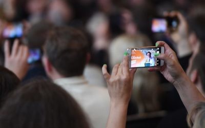 Visitors take pictures with mobiles of German Chancellor Angela Merkel delievring her speech in front of a poster featuring Conservative Christian Democrats (CDU) leader in North Rhine-Westphalia Armin Laschet during a CDU campaign rally for state elections in North Rhine-Westphalia on May 5, 2017 in Bonn, western Germany. (Patrik Stollarz/AFP)