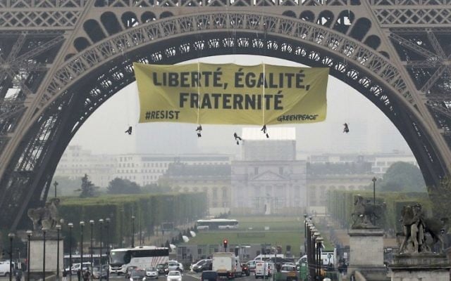 A photo shows a banner reading "liberty, equality, fraternity" hung by Greenpeace activists on Eiffel Tower in Paris early on May 5, 2017, to protest against the far-right Front National (FN) party, two days before the second round of the presidential election. (AFP PHOTO / Jacques DEMARTHON) 
