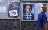 A man walks past election posters plastered close to a polling station in Saint-Leu, Reunion, on May 7, 2017, during the second round of the French presidential election. (AFP Photo/Richard Bouhet)