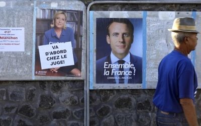 A man walks past election posters plastered close to a polling station in Saint-Leu, Reunion, on May 7, 2017, during the second round of the French presidential election. (AFP Photo/Richard Bouhet)