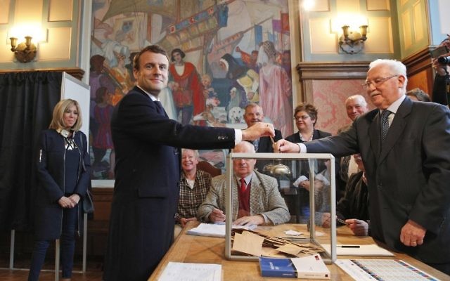French presidential election candidate for the En Marche movement Emmanuel Macron casts his ballot as his wife Brigitte Trogneux looks on at a polling station in Le Touquet, northern France, May 7, 2017. (AFP/POOL/Christophe Ena) French presidential election candidate for the En Marche movement Emmanuel Macron casts his ballot as his wife Brigitte Trogneux looks on at a polling station in Le Touquet, northern France, May 7, 2017. (AFP/POOL/Christophe Ena)
