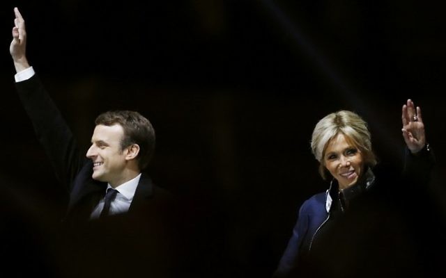 French president-elect Emmanuel Macron, left, waves to the crowd next to his wife Brigitte Trogneux in front of the Pyramid at the Louvre Museum in Paris on May 7, 2017. (AFP/ Patrick KOVARIK)
