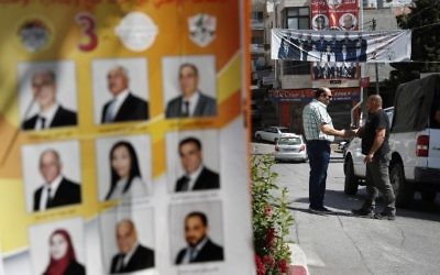 Palestinians stand near campaign posters displaying electoral lists ahead of municipal elections in the West Bank city of Bethlehem on May 10, 2017. (AFP/Thomas Coex)